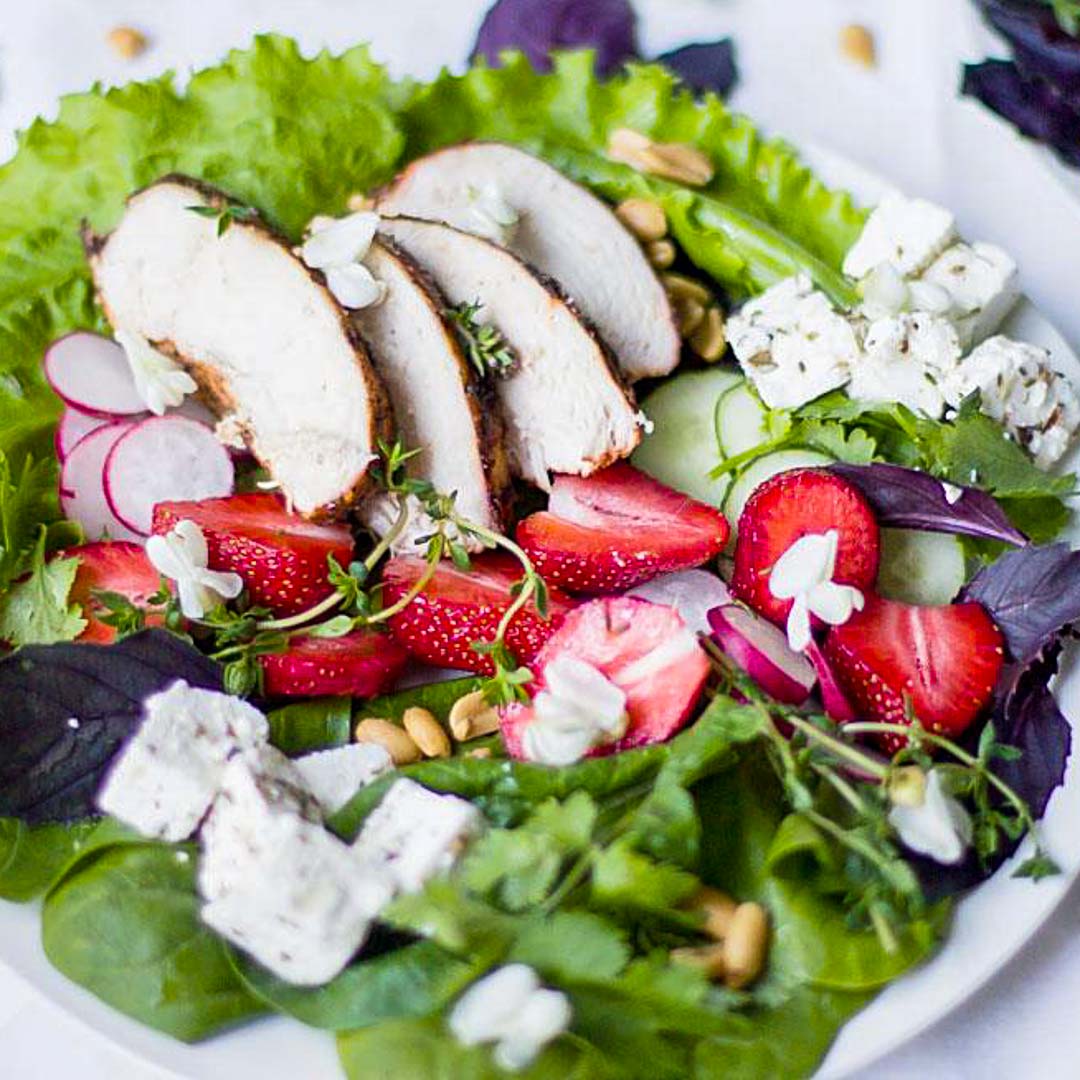 Serving healthy and delicious Chicken Feta Strawberry Salad on a big white plate