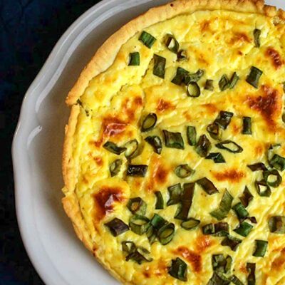 Quiche au Camembert or Camembert Cheese Quiche ready and served on a white plate on a dark blue cloth