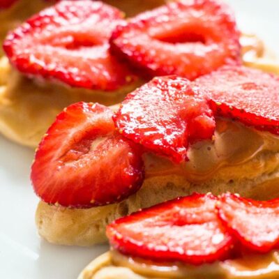 Eclairs with Caramel Topping Cream & Strawberries on a white plate Closeup