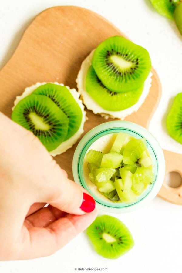 Grabbing a small jar full of the mouthwatering Kiwifruit Cheesecake recipe with a couple of cupcake bites laying right next to the glass jar
