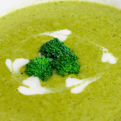 Creamy Broccoli Soup with super green healthy broccoli in the middle of a bowl and cream hearts around it