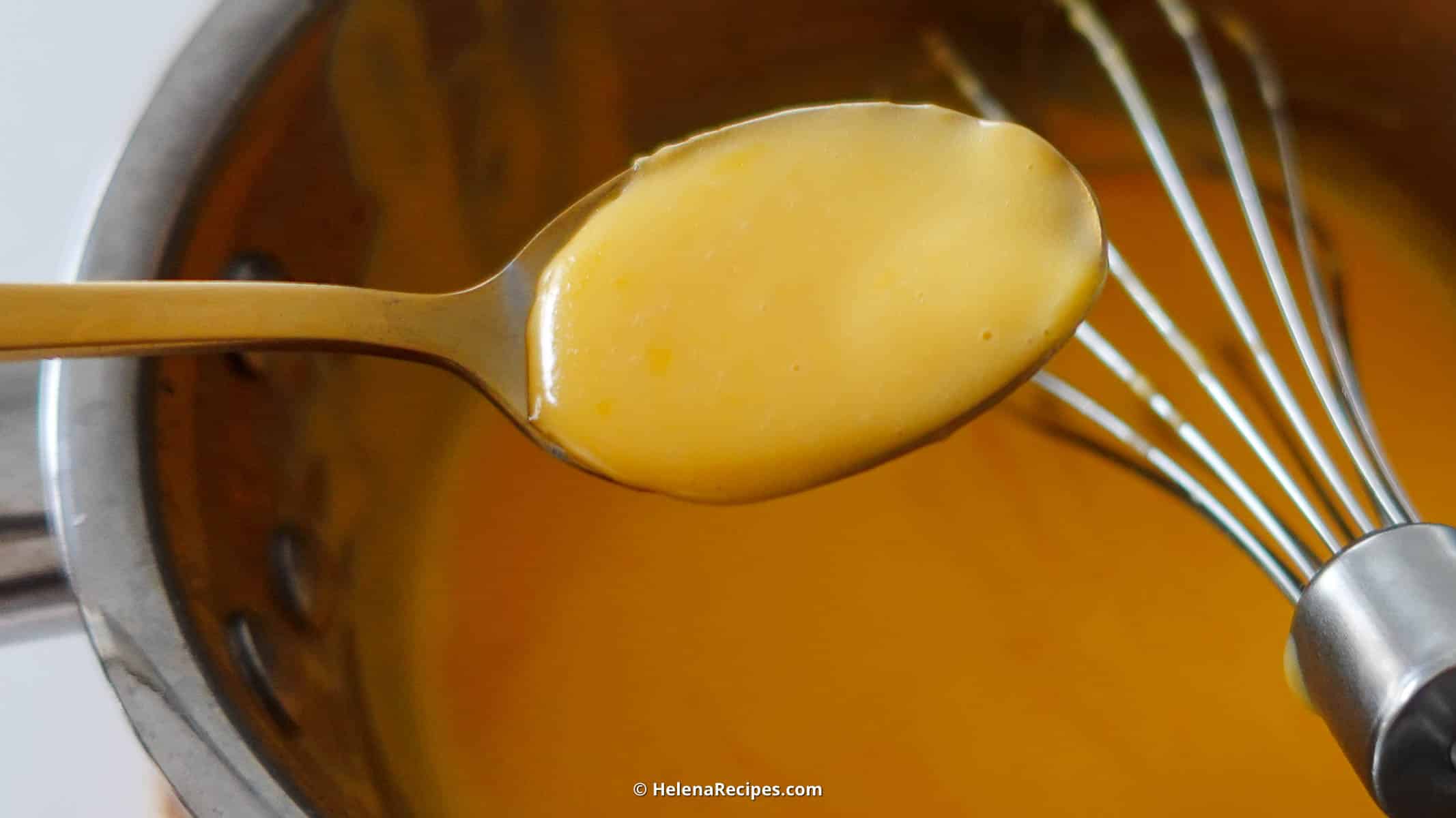 Hollandaise Sauce in a bowl with a full spoon of sauce.