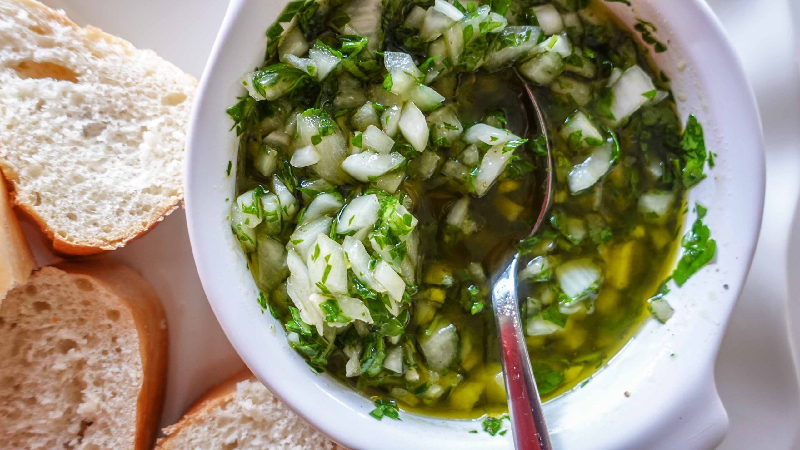 Portuguese salsa verde in a bowl with bread pieces.