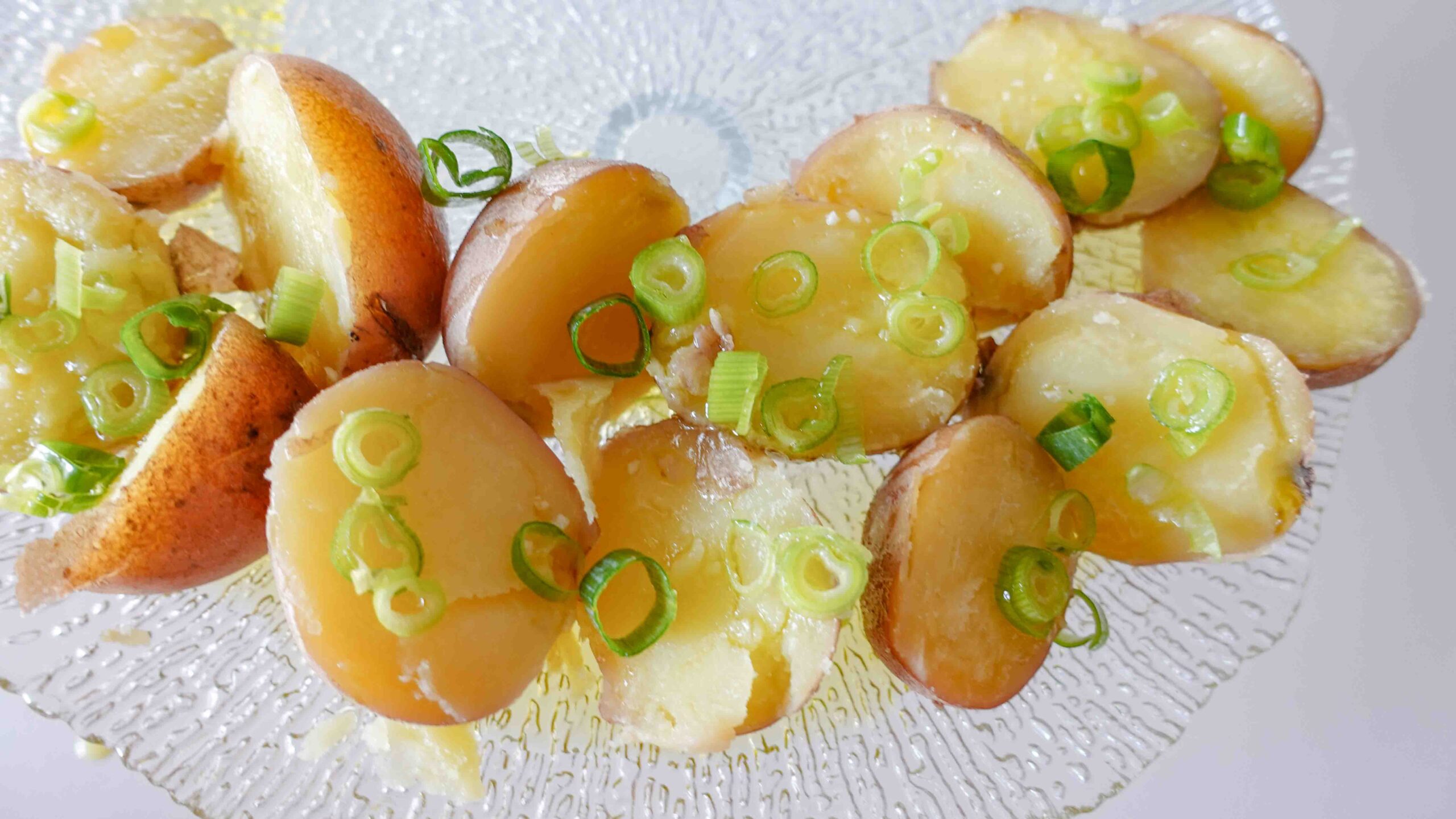 Cooked potatoes on a plate with green onion.
