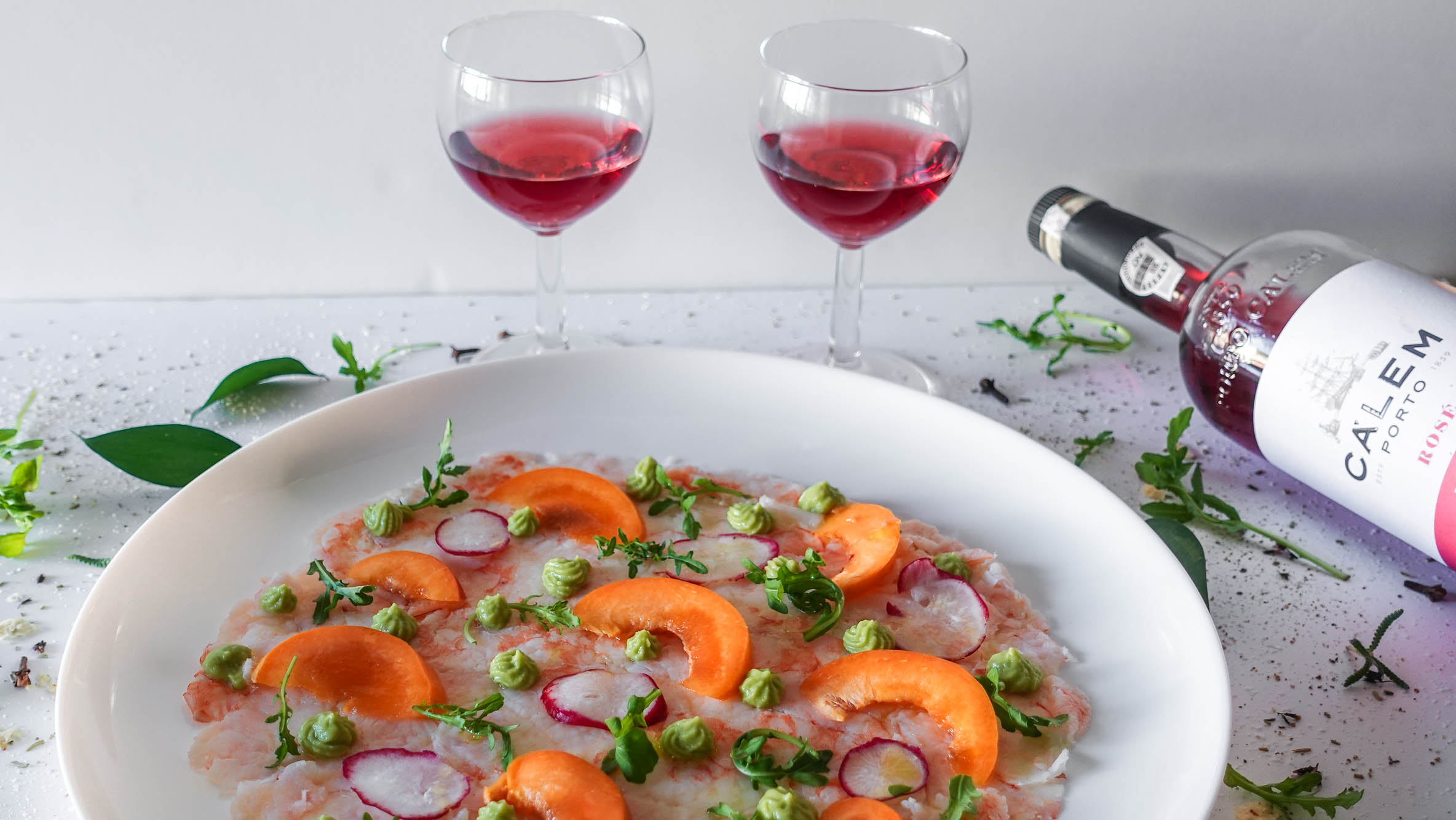 Apricot Shrimp Carpaccio on a plate with two glasses of port wine