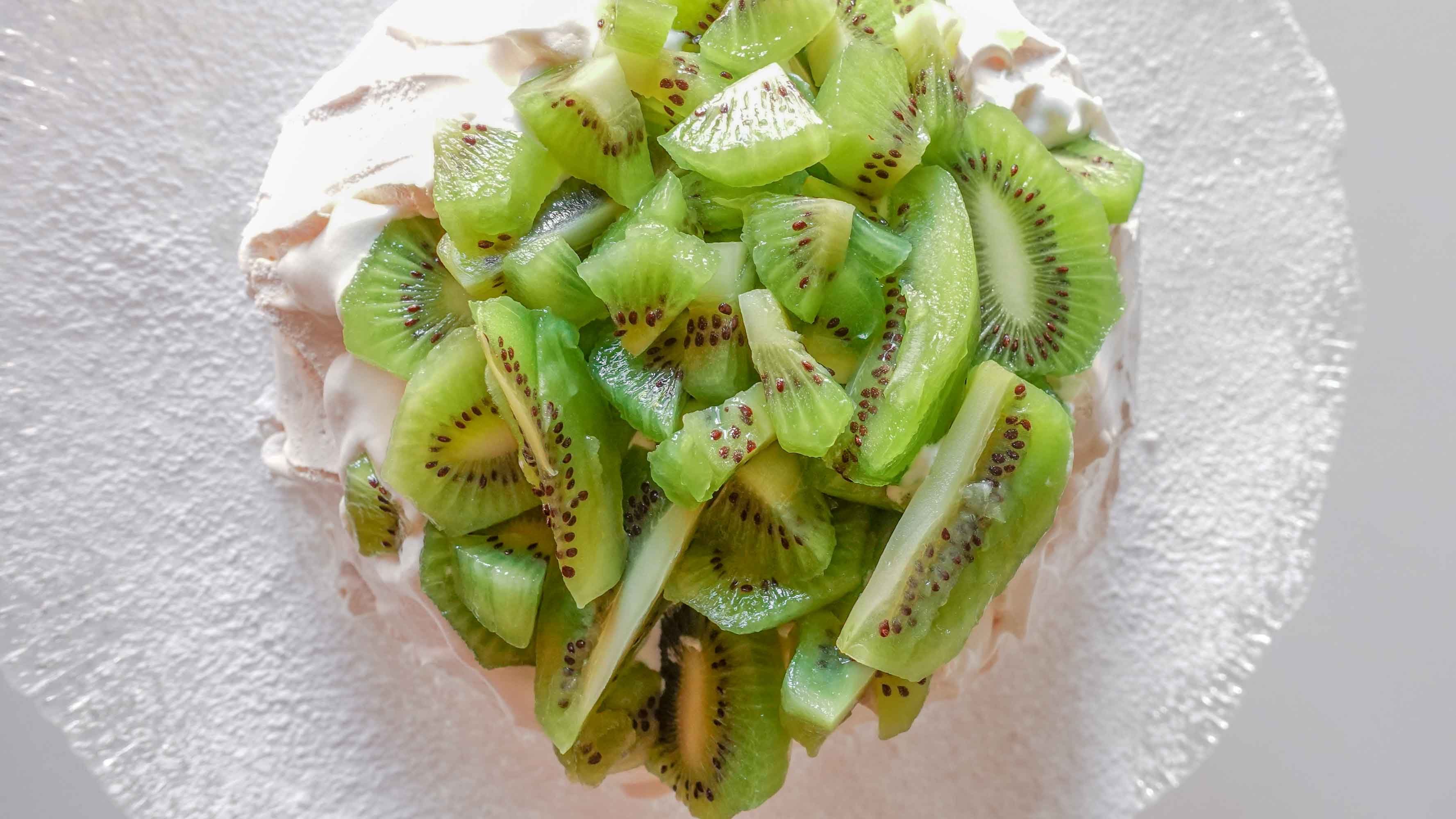 Kiwi Pavlova on a plate with icing sugar