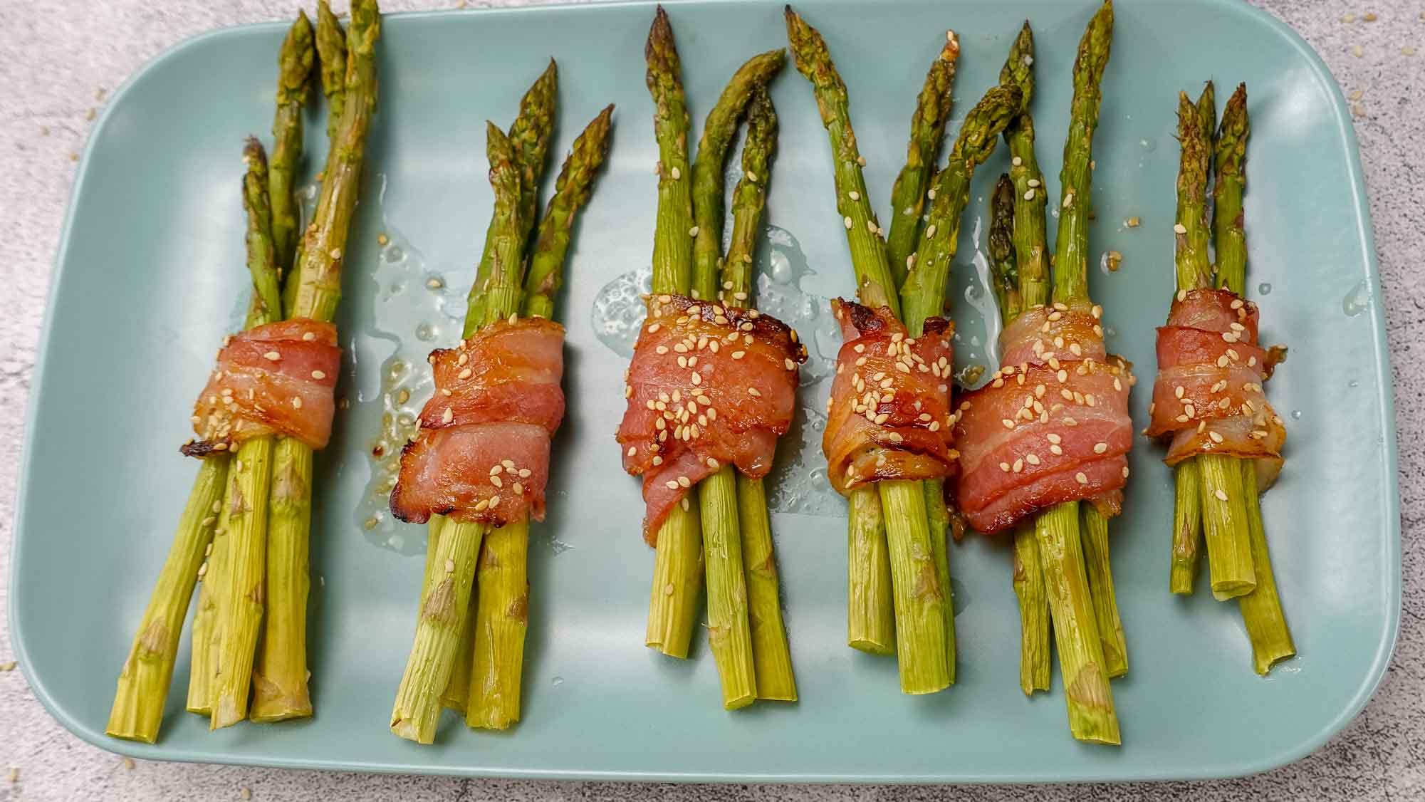 Bacon Wrapped Asparagus Recipe on a blue plate.