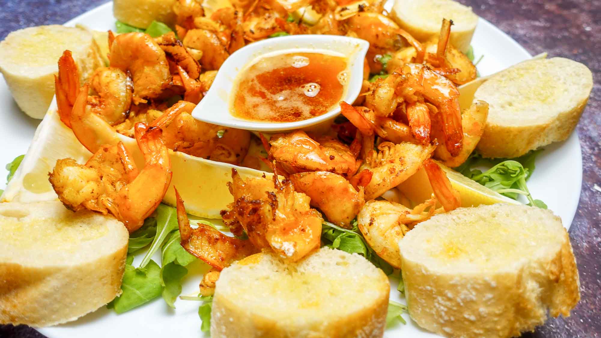 Garlic Butter Shrimp on a plate with bread toasts.
