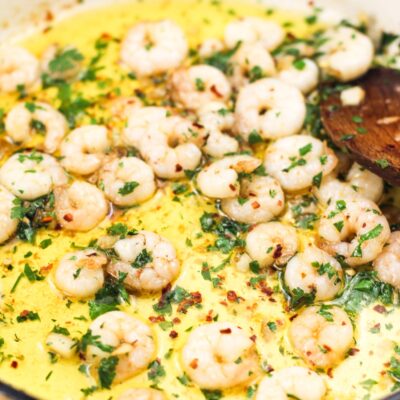 Shrimp in a pan with olive oil with a spoon.